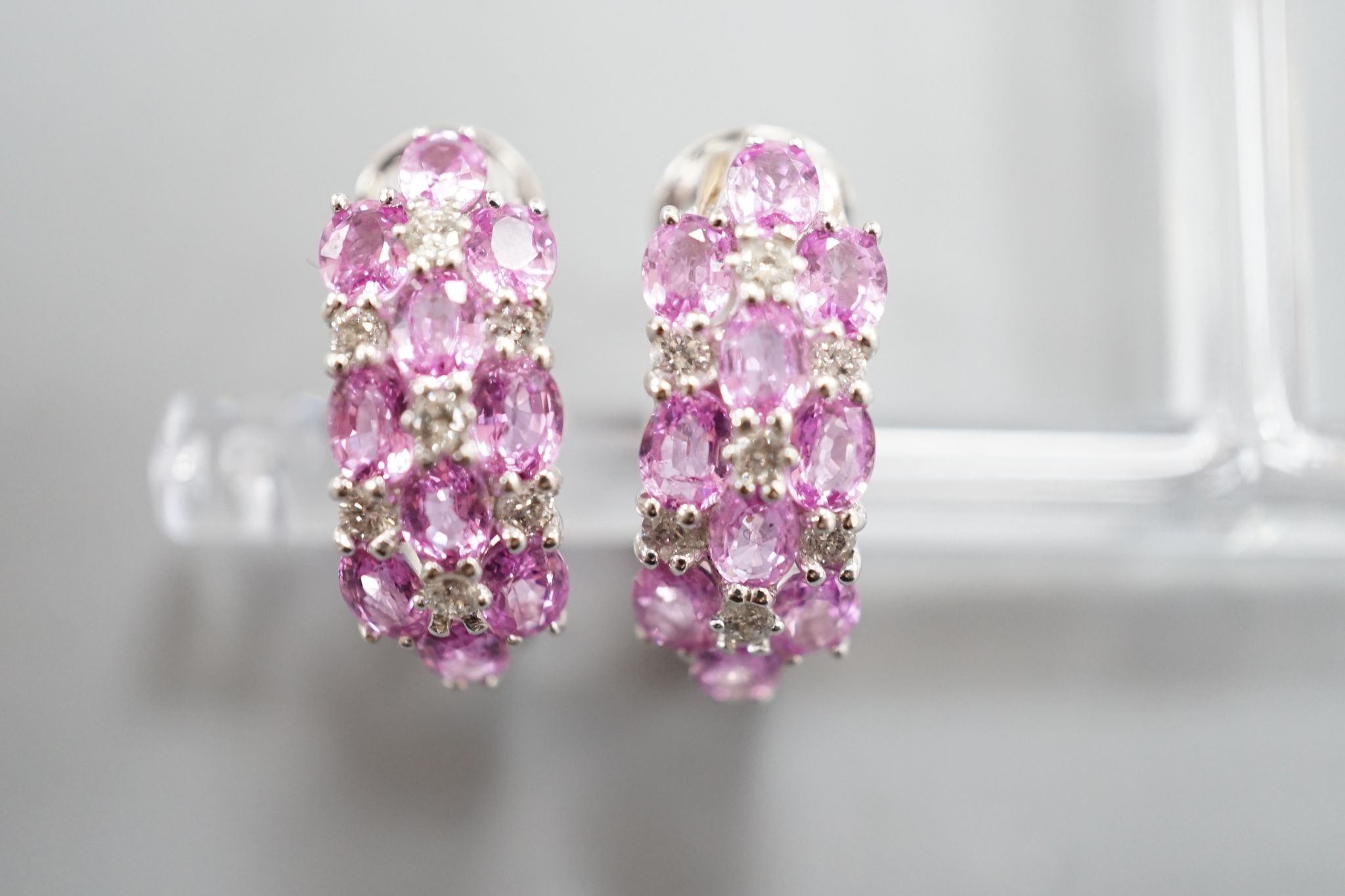 A modern pair of 14k white metal, pink sapphire and diamond cluster set half hoop earrings, 17mm, gross weight 8.3 grams.